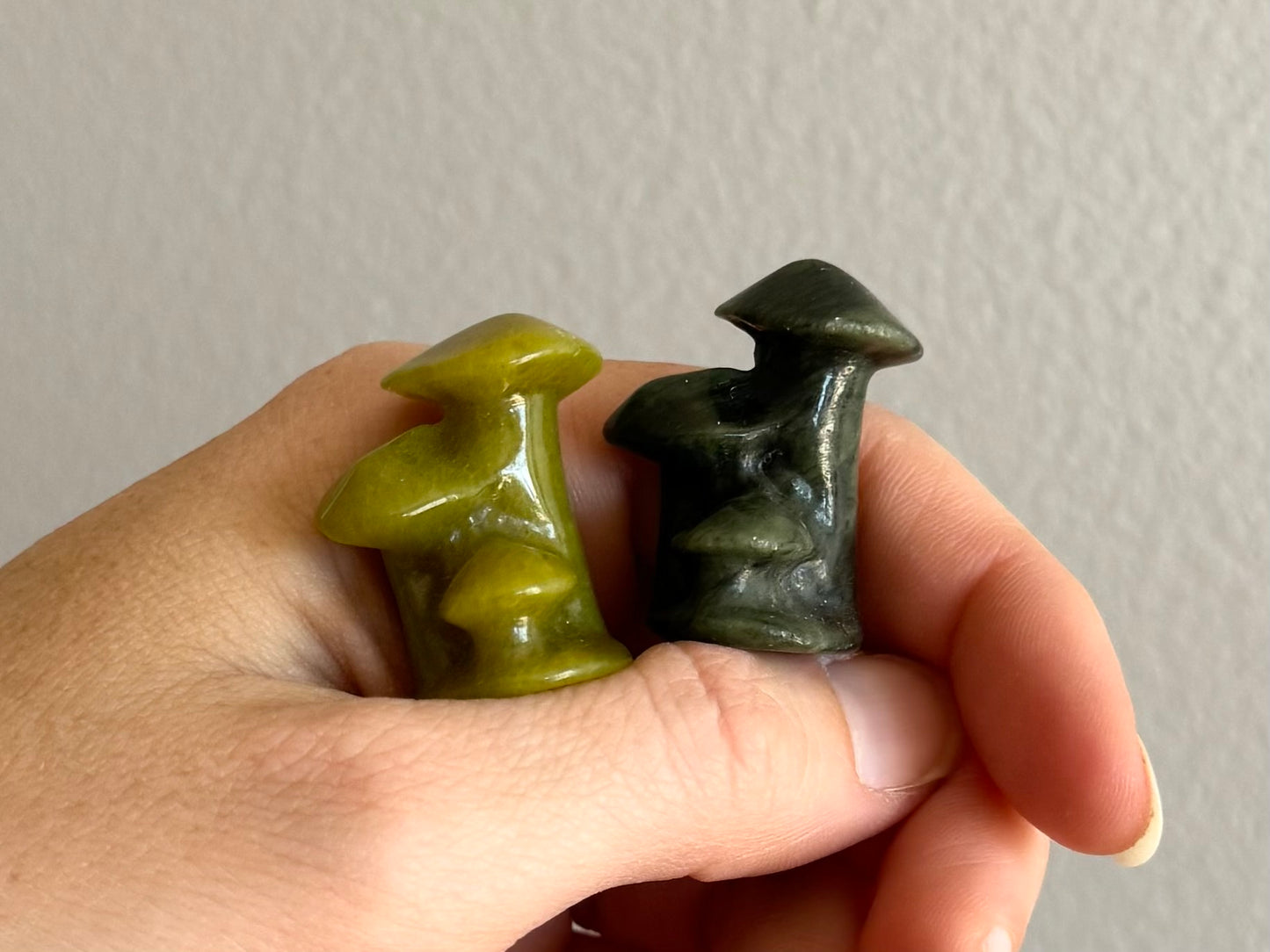 One each of the light and dark green mushroom trios on a hand for scale, set on a thumb and resting against the index finger.