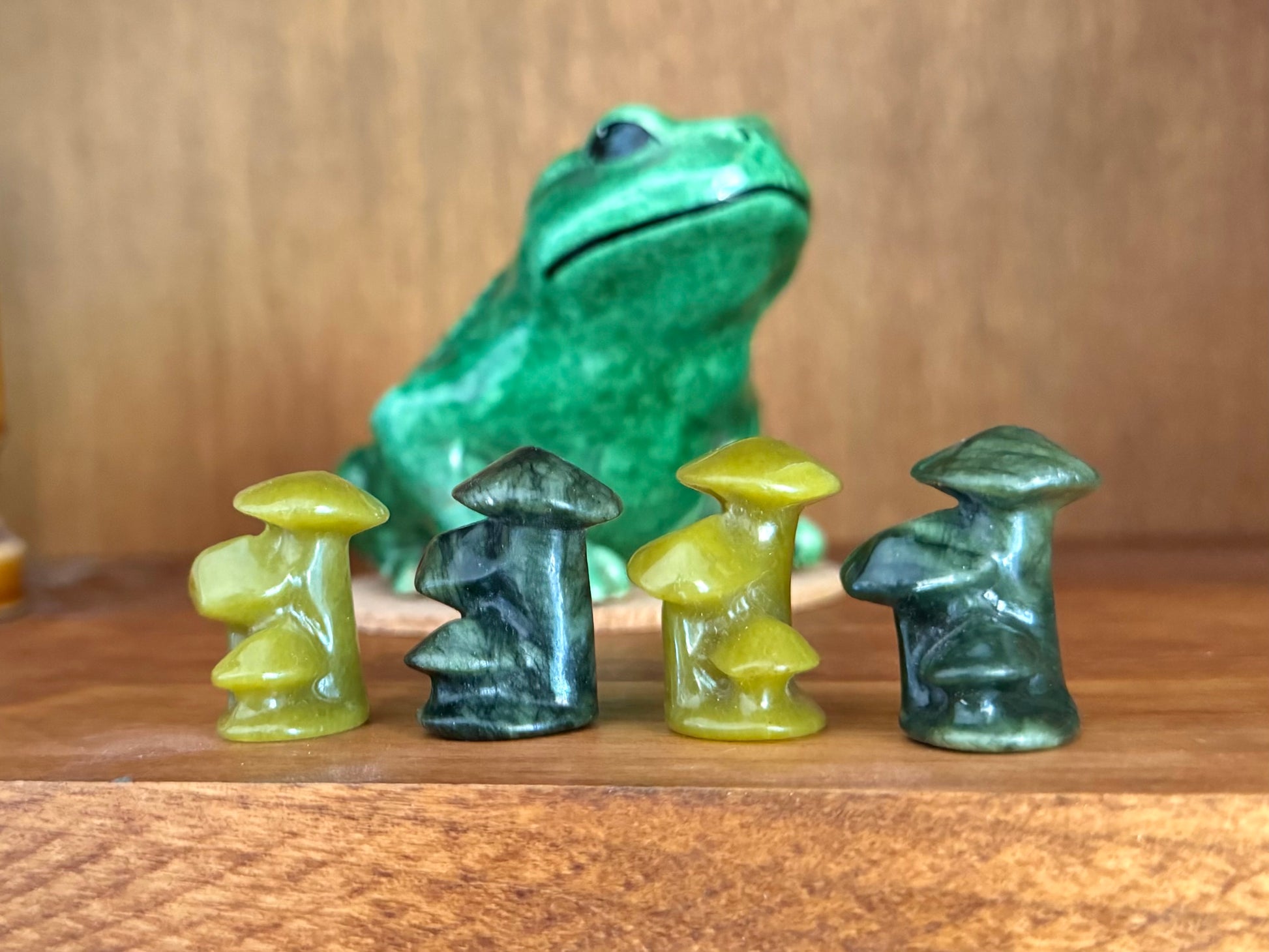 Four mushroom trios, lined up alternating light and dark colors. There is a ceramic frog in the background.