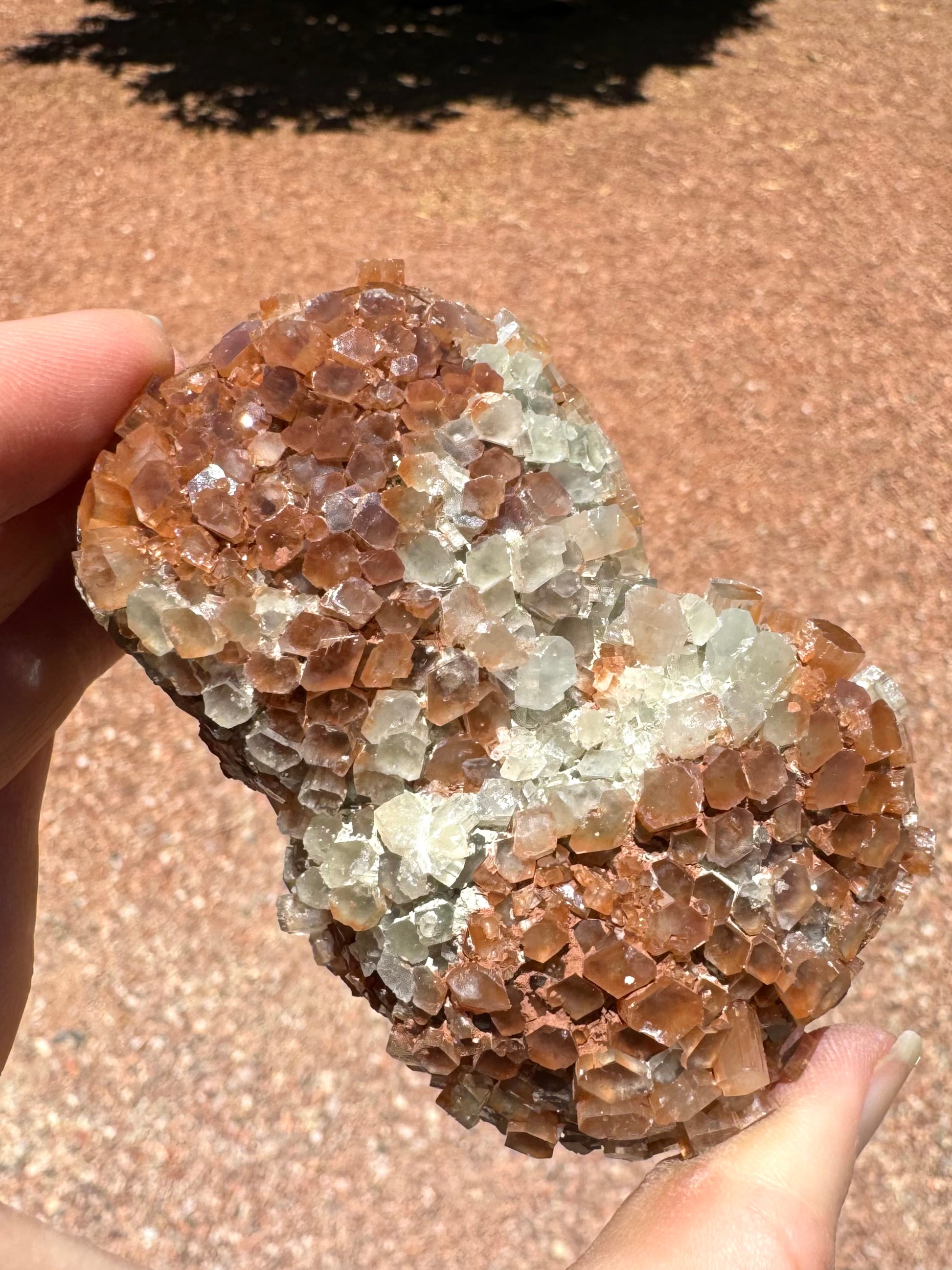 Closer view of the side of the piece with well-formed crystals, showing large crystal size and good geometry. There are some white and red opaque minerals deposited between crystals.