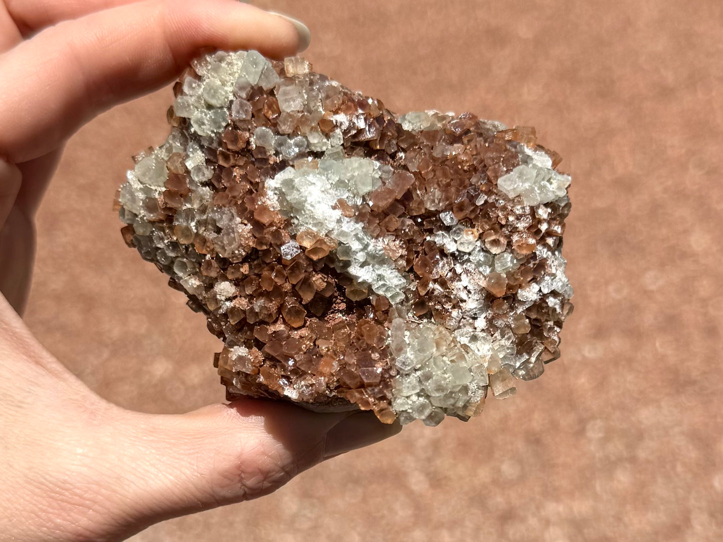 An irregularly shaped side of the piece, with haphazardly arranged crystals. There are some broken crystals and also some white overgrowth in areas.