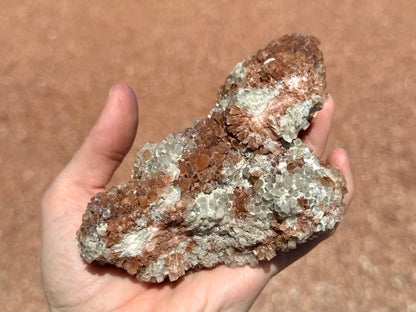 The bottom of the piece, with some rough crystals and two flat breaks. The breaks have exposed the red-and-white radial patterns of the crystal growth. There is fine opaque white mineral dusting this side and deposited between minerals.