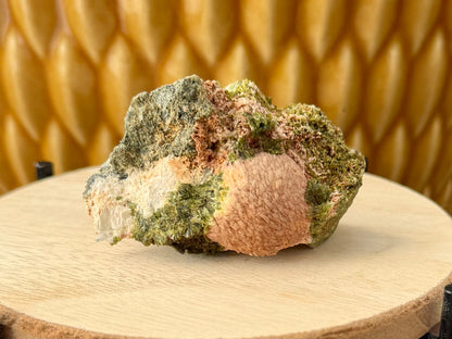 A specimen with some roughly-formed epidote on a grainy rock matrix, and a large opaque sphere of prehnite.