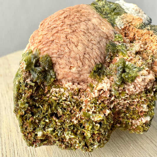 Detail of a prehnite sphere, the surface composed of rectangular faces of the tops of crystals like a brick road. There are good epidote bow ties around the sphere, and a mix of epidote and light-colored crystals covering the surface.