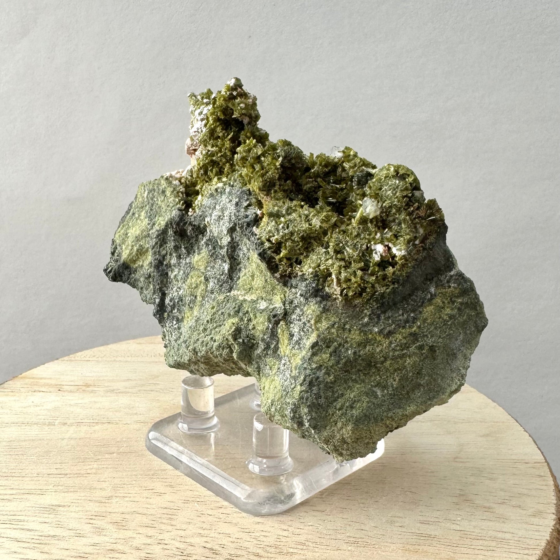 Angled view of the piece showing the contours of the matrix and the luster of the epidote on the top of the piece. 