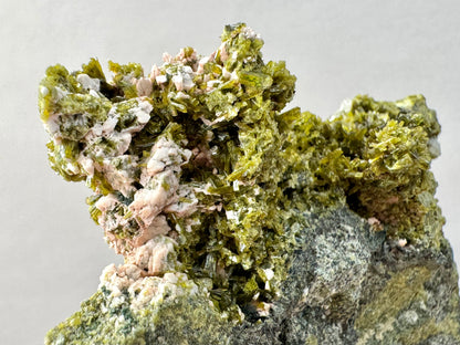 Detail of epidote crystals on one end of the specimen, with a chunky opaque mineral growing on them.