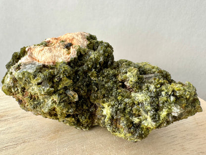 The specimen covered with a dense layer of epidote crystals, with several small clear quartz crystals mixed in.