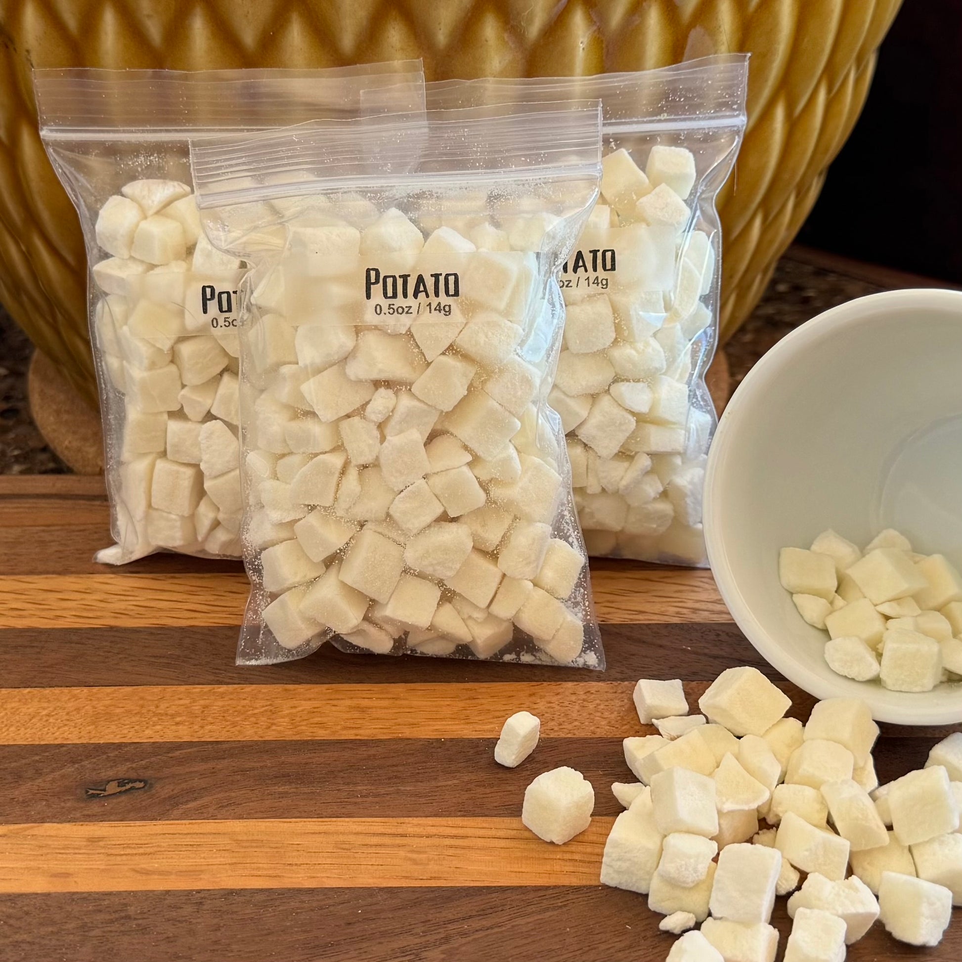 Several bags filled with white cubes, labeled "Potato 0.5oz / 14g," with a small bowl to the right spilling dried potato cubes