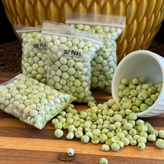 Several bags filled with peas, labeled "Freeze-dried Peas 1.25oz / 35g," with a small bowl to the right spilling dried peas