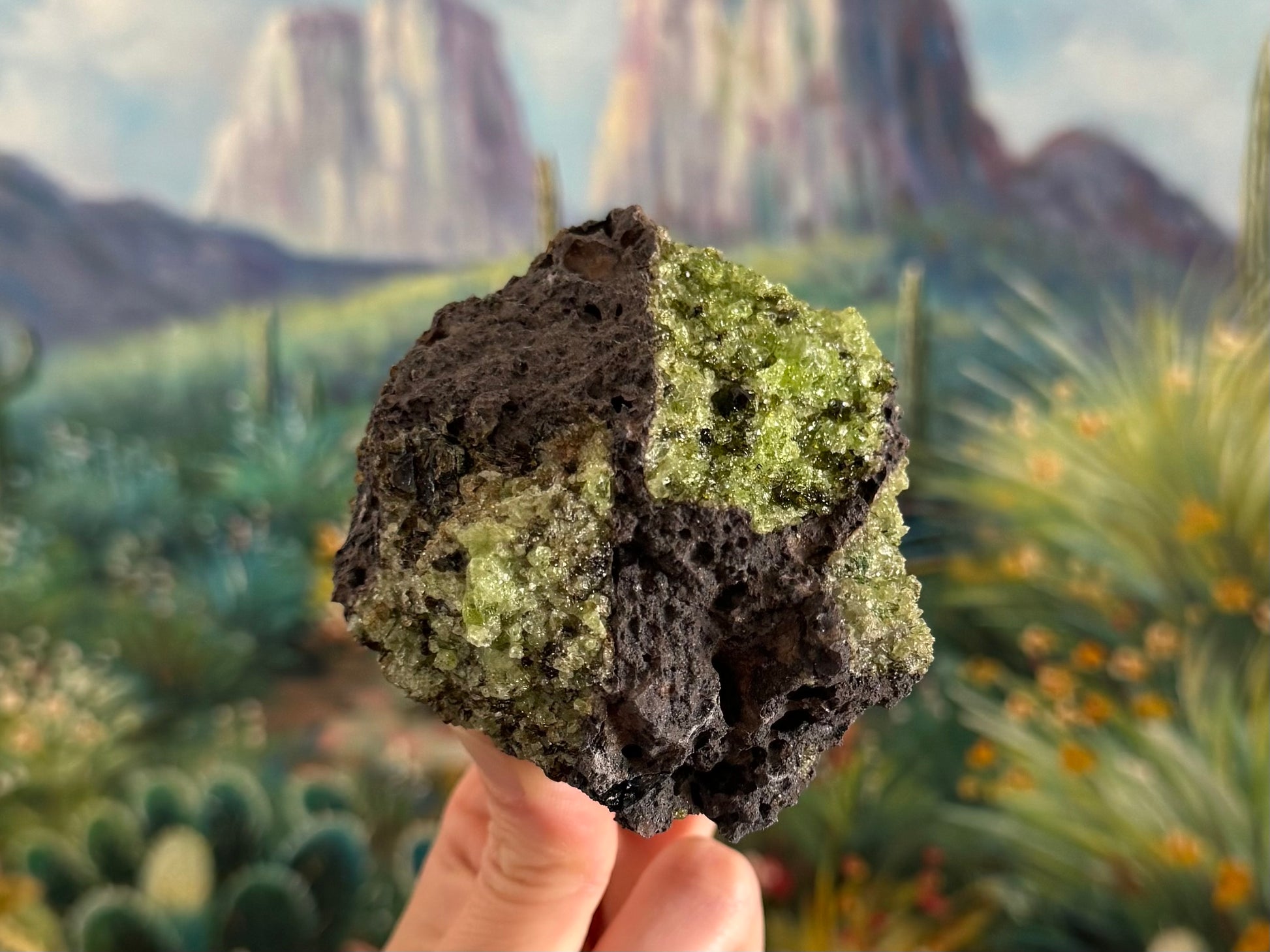 A roughly round chunk of dark gray porous volcanic basalt with a large patch of peridotite on the top right and a symmetrical patch in the bottom left