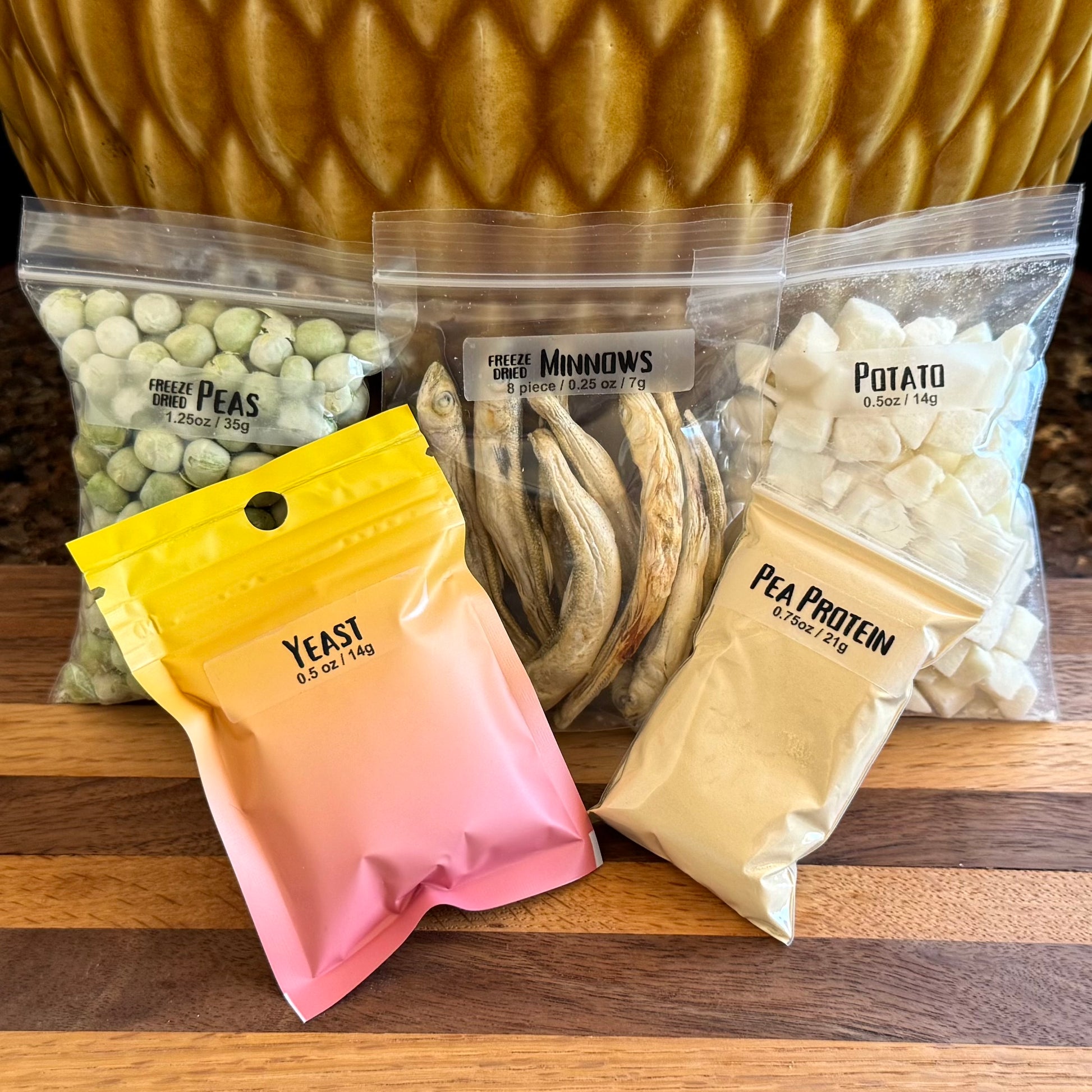 One of each of the bags from the previous images: peas, minnows, potato, yeast, and pea protein. The yeast and pea protein powder are both in smaller bags than the other foods.