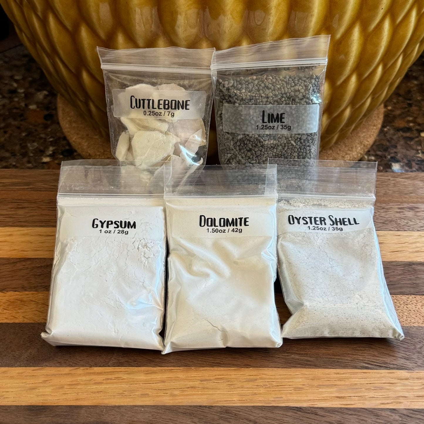 One of each of the options from the previous images: a small bag of crushed cuttlebone, lime pellets, gypsum, dolomite, and oyster shell. The bags are small and all the same size.