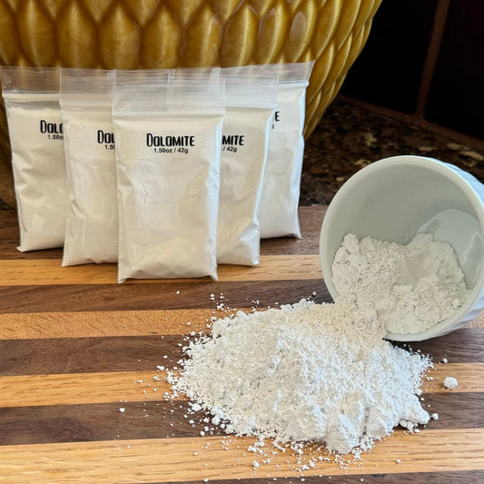 Several small plastic ziploc bags labeled "Dolomite 1.50oz / 42g." To the right is a small white bowl on its side spilling a white powder.