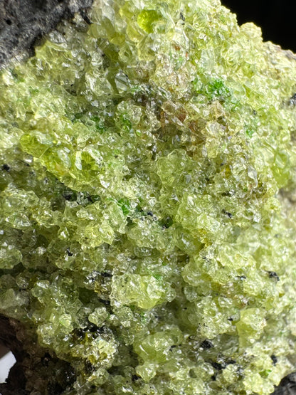 Detail view of the peridotite, a patch that is mostly light yellow-green in color with some larger gemmy crystals.