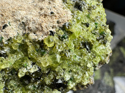 Close detail of the composition of the green minerals. There are large light yellow-green crystals of olivine, with some dark forest green pieces of spinel and small pieces of vivid green diopside sprinkled through.