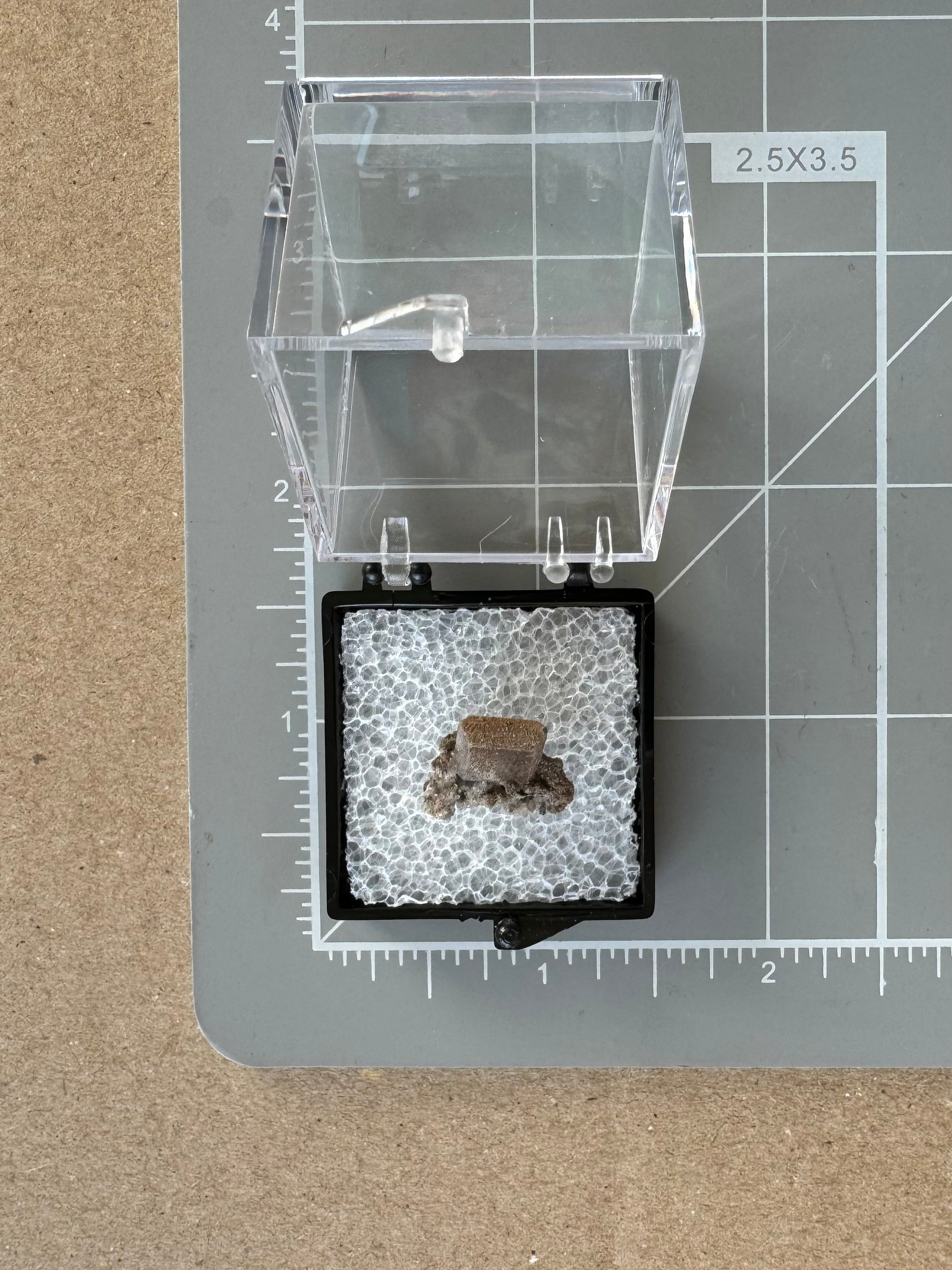 Scale image of the piece on a measuring mat. The thumbnail box is one and a quarter inches, with the specimen measuring less than half and inch with the crystal about a centimeter.