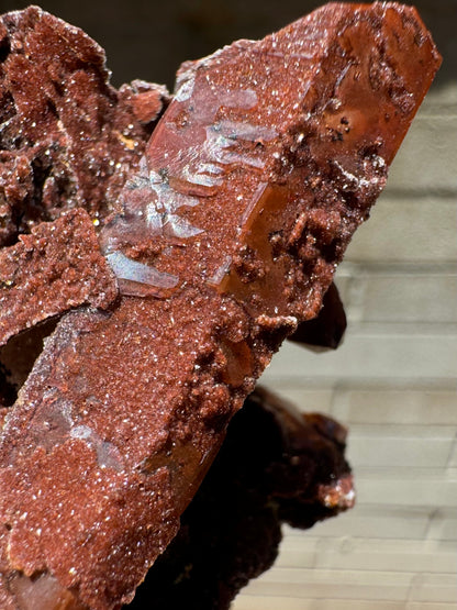 Detail of the base of the quartz point at an angle, with light reflecting off the surface. It has muted luster, with an almost rippled surface. The druzy has good glitter.