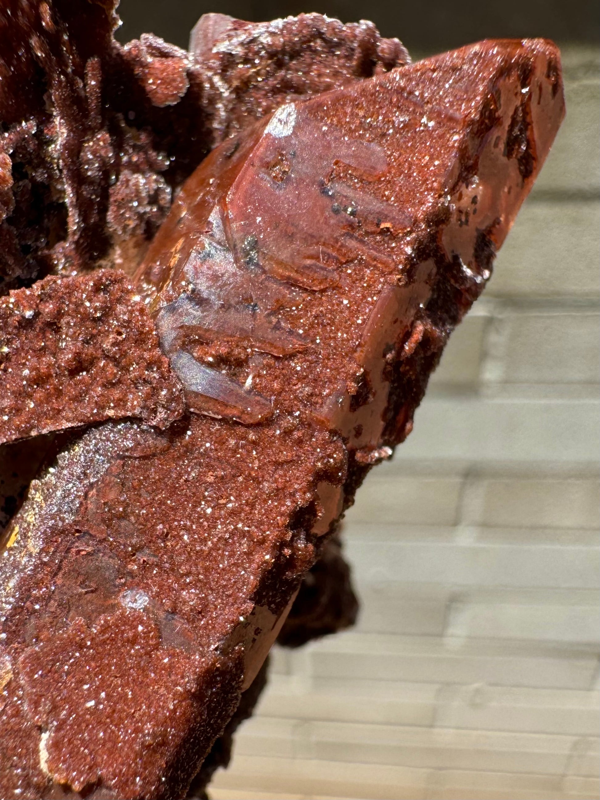 Detail of the base of the quartz point, with a red druzy layer partially covered with a raised colorless layer with poor luster.