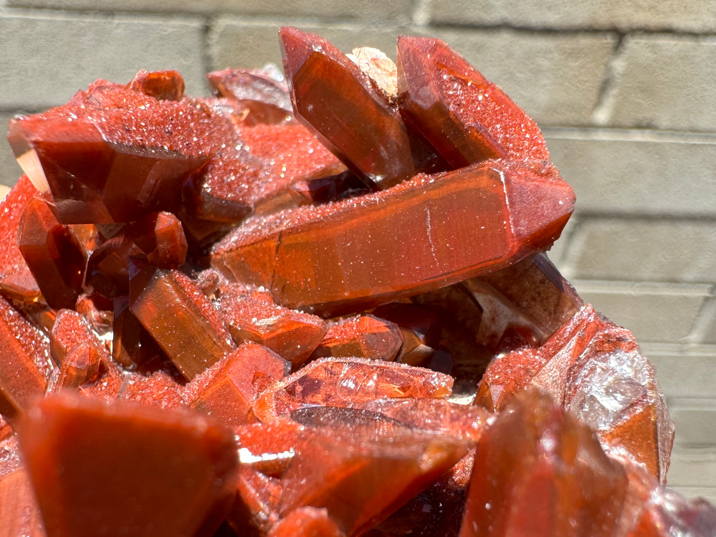 Detail of several red quartz points, with an opaque red internal coloration and a glossy top layer, creating an odd phantom effect.