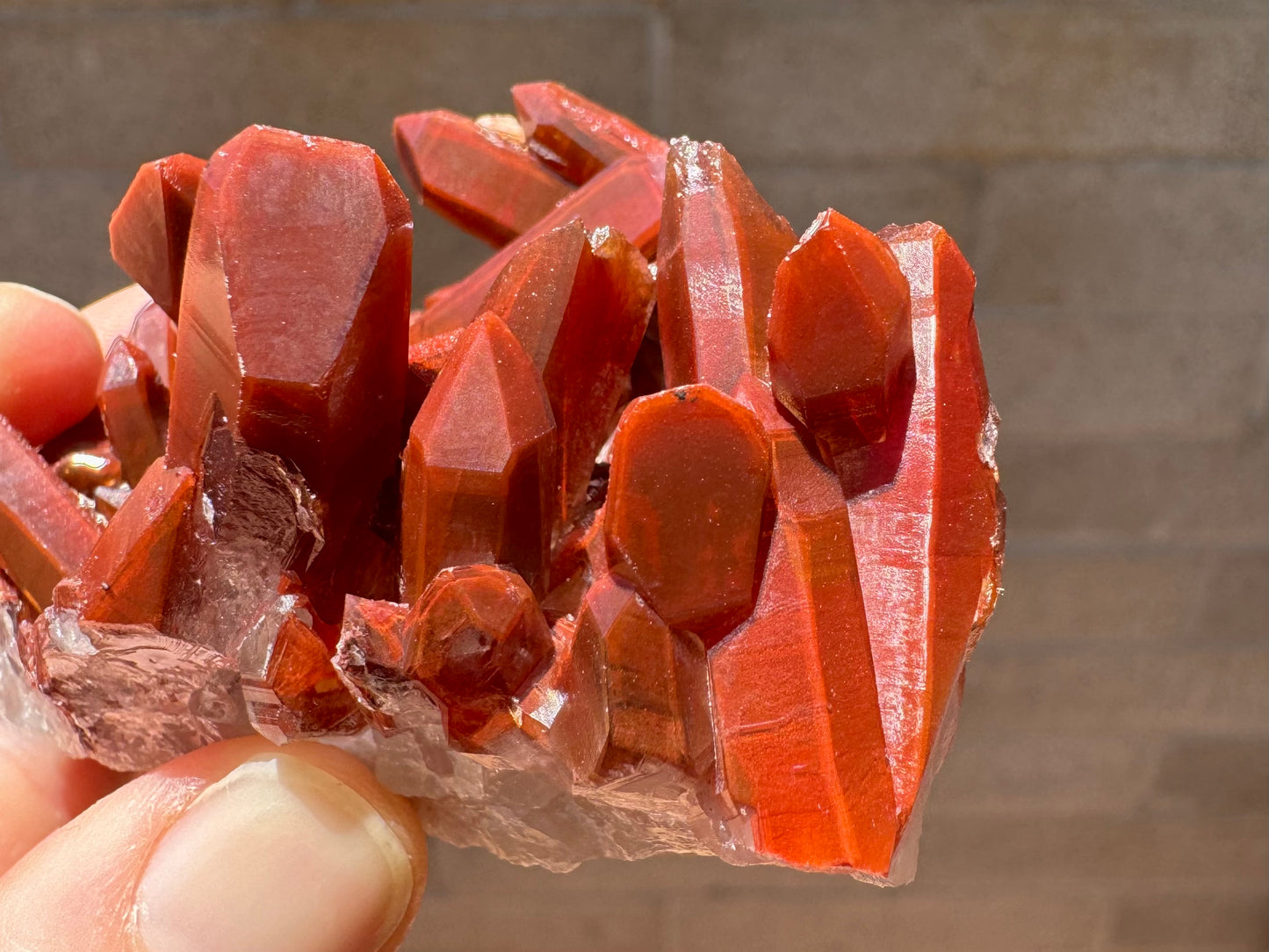 Detail of quartz points of alternating orientations, intersecting. They have a matte red color with some sheen.