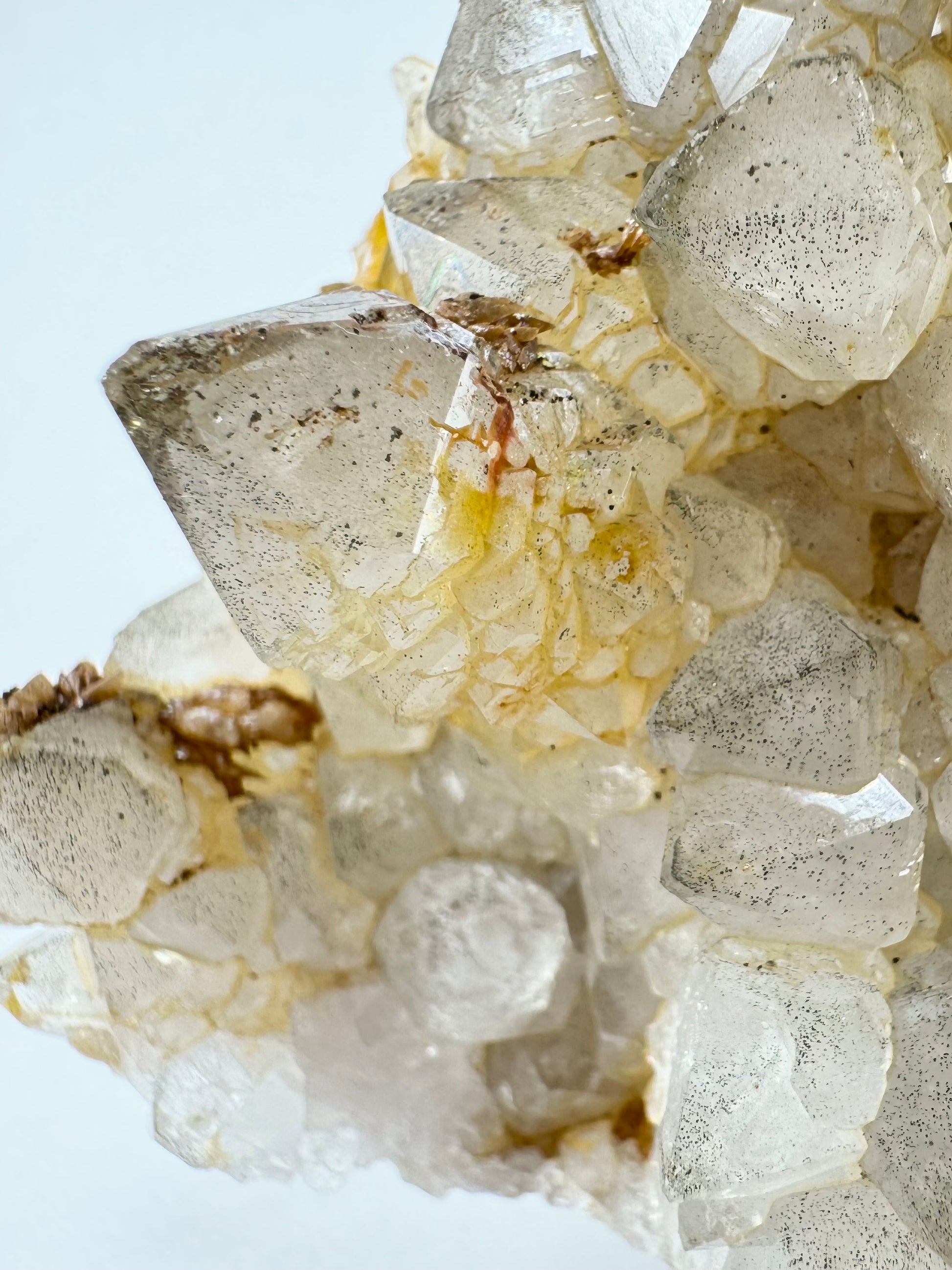 Detail of milky phantom growth inside colorless quartz points spotted with fine black inclusions, and with iron staining emphasizing the textured sides.