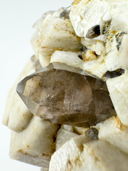 Close view of the smoky quartz crystal, with several smaller ones around it. The main crystal is lightly included with good color and clarity, and an in-tact point