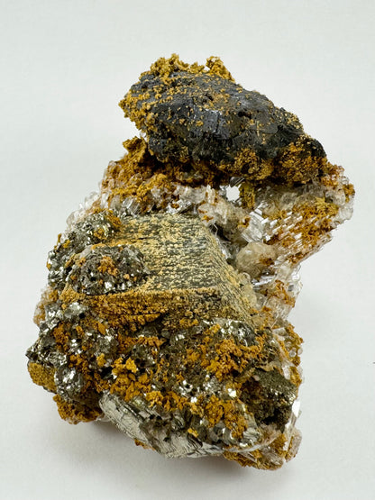 The underside of the specimen, a conglomerate of different minerals including a dull dark gray galena and a shiny gold pyrite, with golden siderite sprinkled across the surfaces.