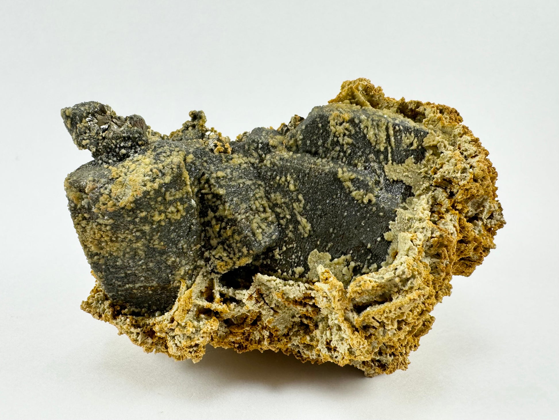 Dark hexagonal crystals in a fanning growth forming the base of the piece, upside down with the siderite on the bottom.