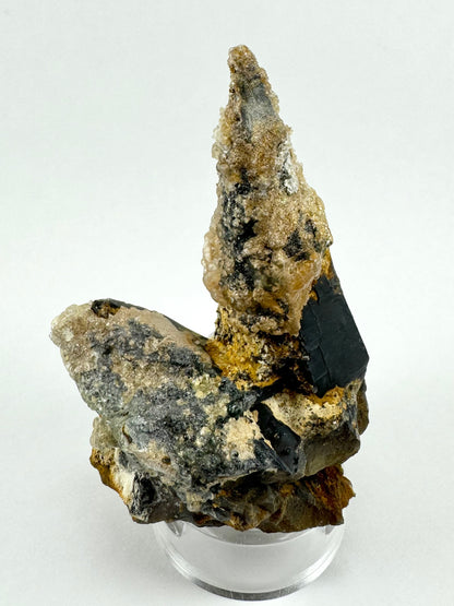 The first of three lighting images: the full specimen, with the partial crystal jutting out to the left, and shard-like crystals on the base. The smoky quartz appears near-black.