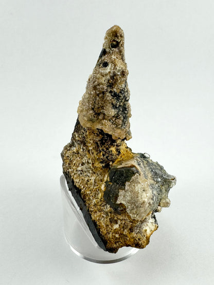 A side-view of the point, showing it is perched on an angled prism covered in small blade-like pieces of a white mineral. The hexagonal shape of the other broken prism is visible.