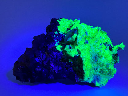 The second of three lighting images: the piece in the same position as the previous image, in the dark and illuminated with UV light. The hyalite fluoresces a strong yellowish-green, with the snowballs especially bright, and a light blue overtone more apparent in thinner areas of hyalite.