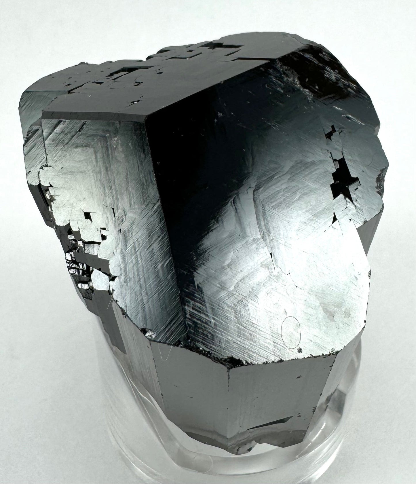 A larger black schorl crystal with Mercedes termination and beveled edges between faces. It has beautiful luster on the top faces, which have intricate hollow diamond-shaped patterns inverted in areas. The luster is glossy and highlights faint three-dimensional angled zig-zag patterns on the surface