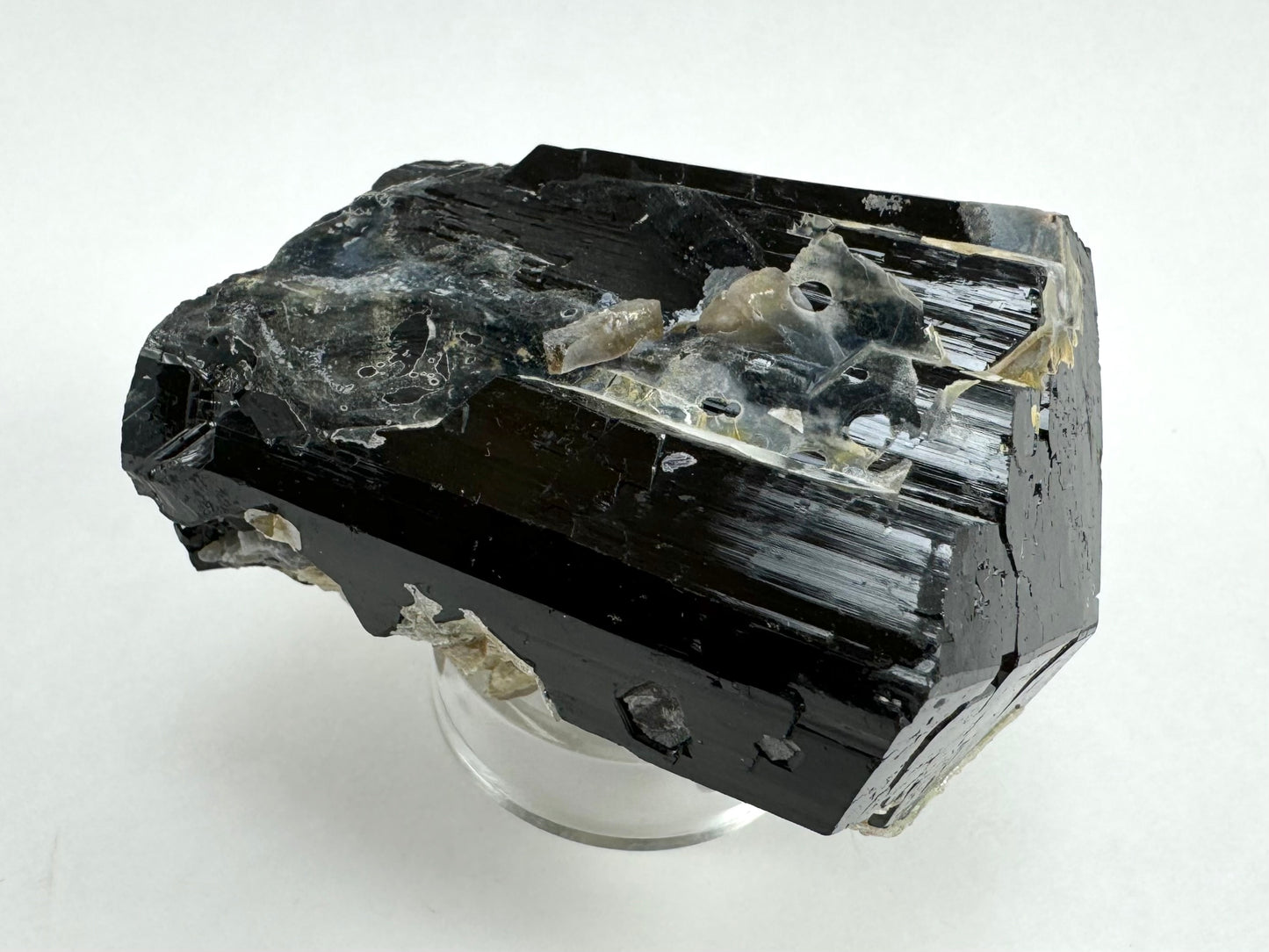 The schorl on its side, with fine vertical striations highlighted in reflecting light. There is some hyalite on this side with good cheese holes.