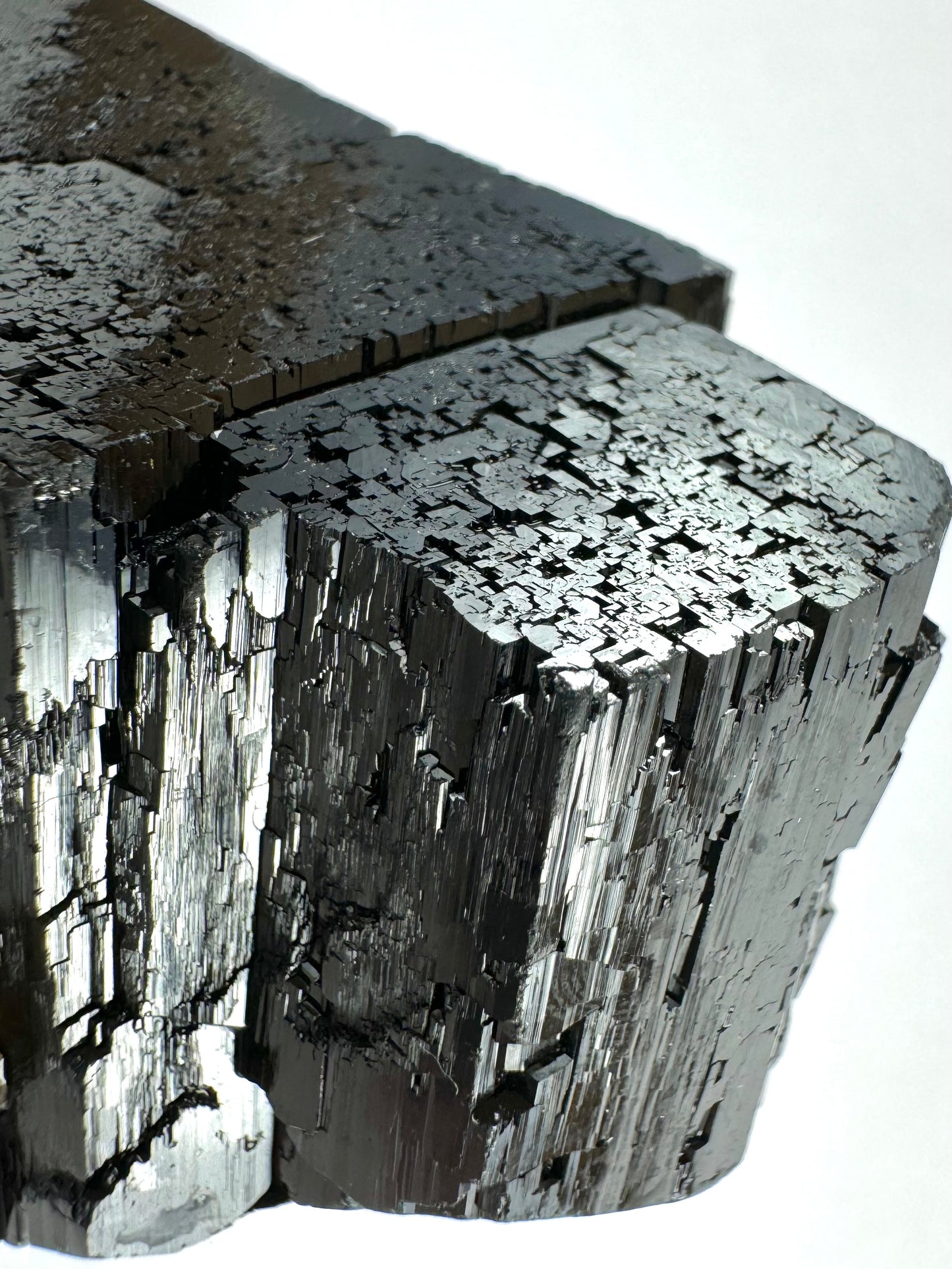 Detail of the smaller of the schorl crystals, with good striations and inverted patterns on the top. A larger crystal is connected behind it.