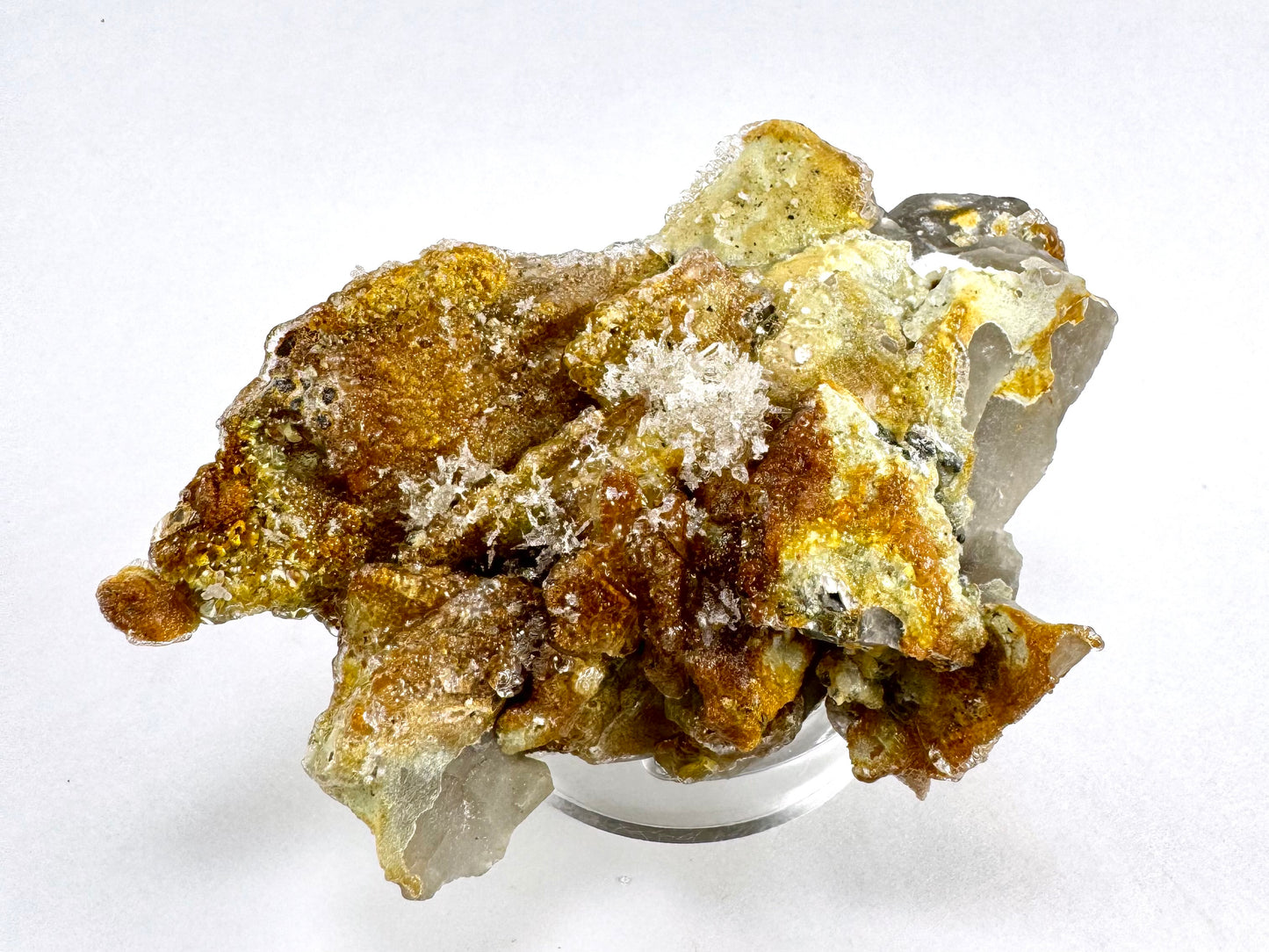 The specimen in the same position as the previous image, in white light. The underside is a rough clump of flat shards of smoky quartz, almost entirely coated in hyalite with thick growth in areas and a lattice-like formation in the center.