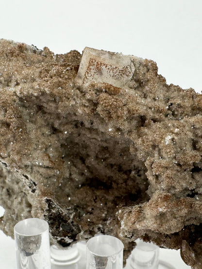 The back of the mineral specimen, covered in glittering tan-colored caclite druzy, with a dusting of lizardite like cinnamon on it. At the top is a well-formed square tablet of hydroxyapophyllite.