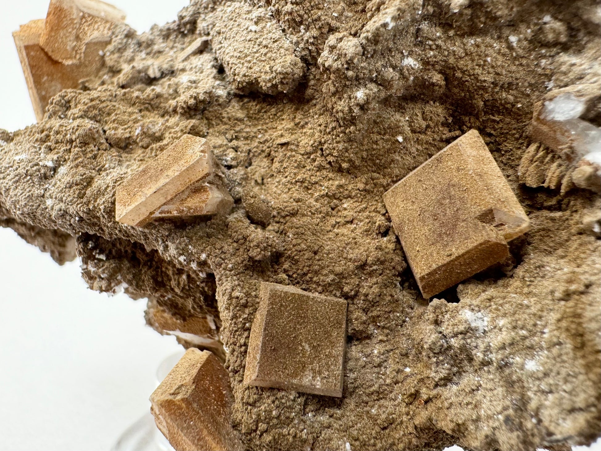 Detail of the square tablet crystals completely opaque and covered with matte lizardite. There is a a cluster of stacked scalenohedral calcite crystals on the left side, mostly covered in the brown mineral.