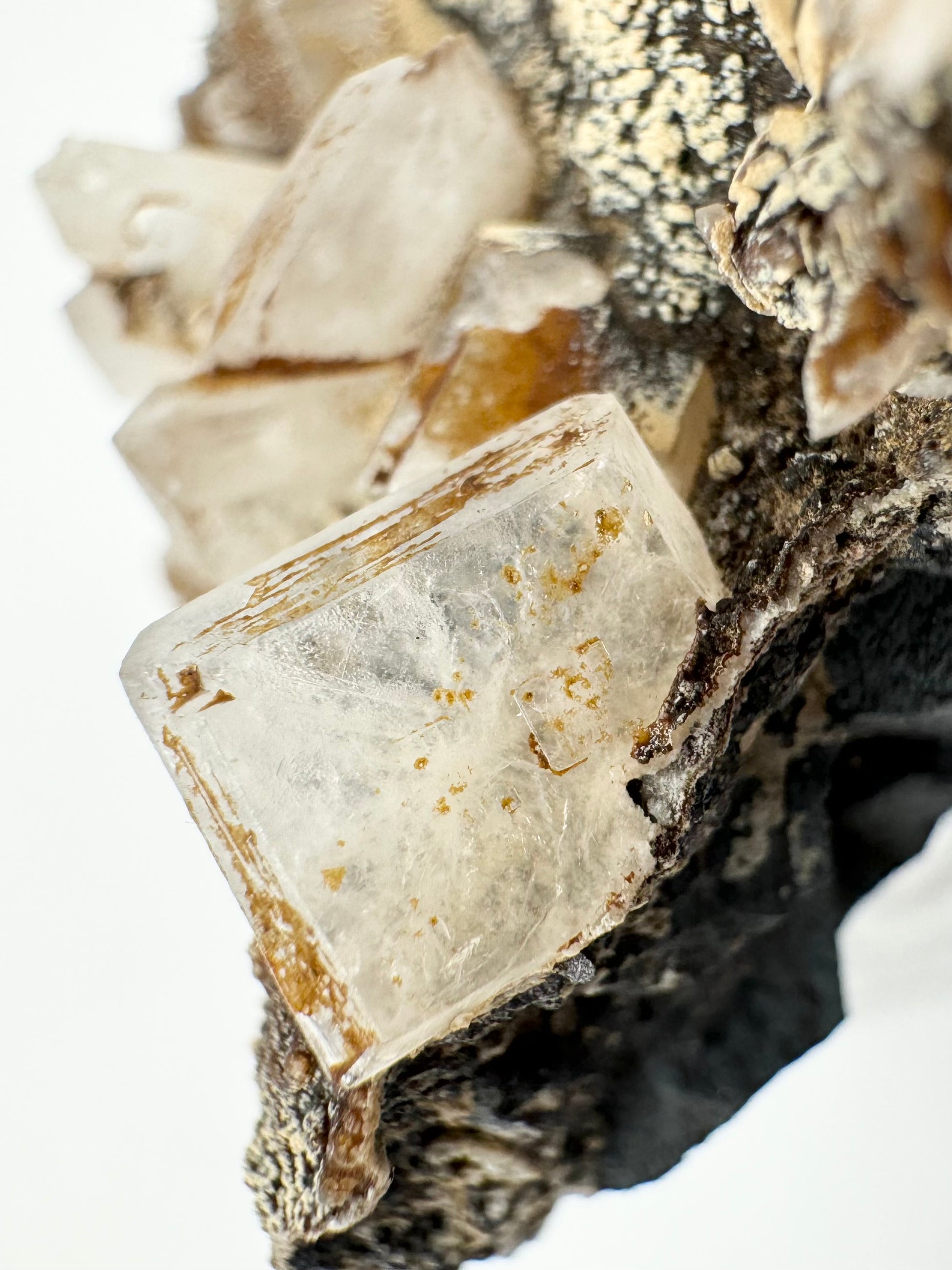 Detail of a hydroxyapophyllite crystal with cubic pattern visible on its surface. Brown staining covers the beveled edges of the crystal.