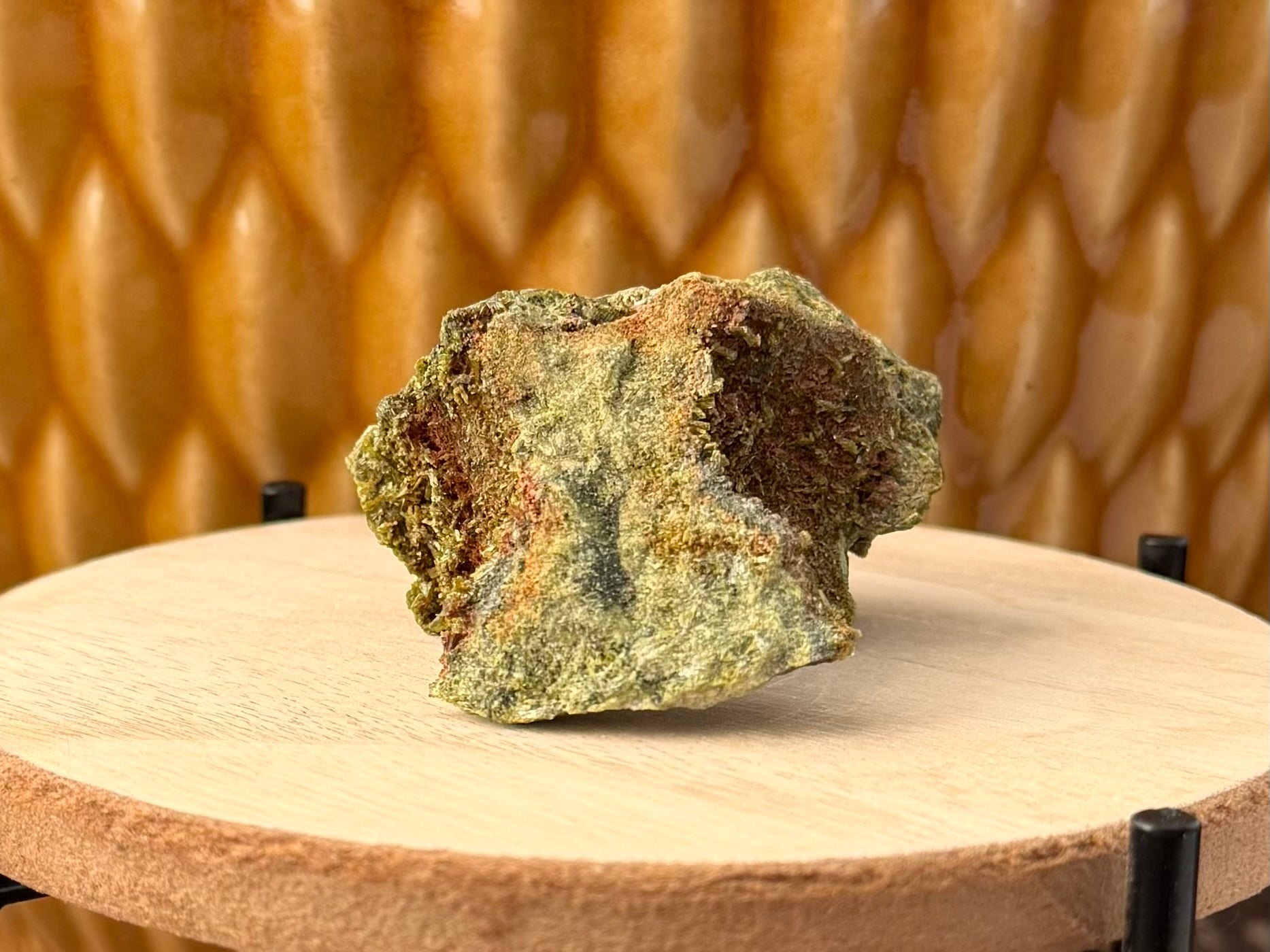 Angled view of the specimen, showing both ends are filled with small epidote crystals in a red-brown matrix.