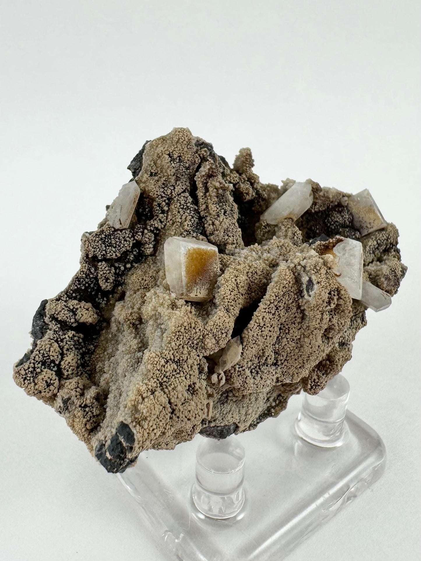 Angled view of the front of the specimen emphasizing the folds in the lumpy matrix, with dark matrix showing through the lighter brown mineral layer