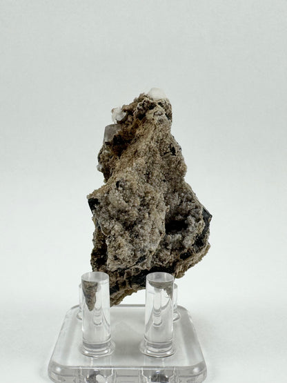 The back of the specimen, irregularly-shape matrix coated in a gray-tan calcite druzy