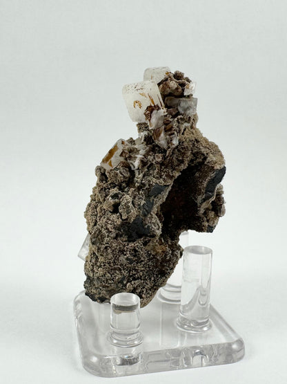 Side-view of the specimen revealing a cave-like dark hole in the side, with the main crystal cluster perched above it.