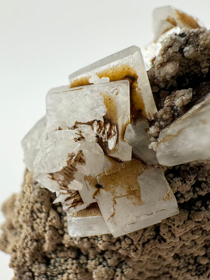 Detail of the cluster of intersecting hydroxyapophyllite crystals, with scalenohedral calcite crystals atop and dark brown iron staining emphasizing the growth lines.