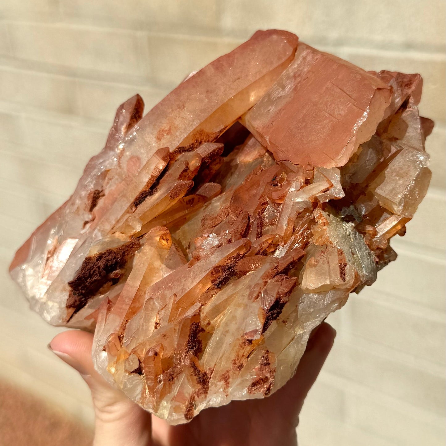 View from the bottom right of the specimen, with many small points clustered at the bottom an some lumpy opaque red overgrowth. The sideways crystal has an irregular end.