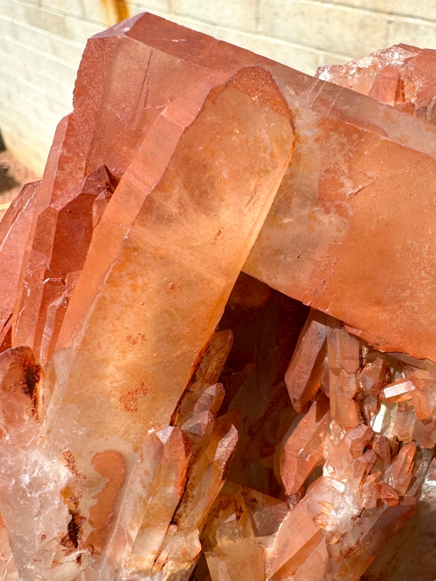 Detail of a large point with good transparency, yellowish with wispy inclusions illuminated inside under the surface layer of orange-red quartz.