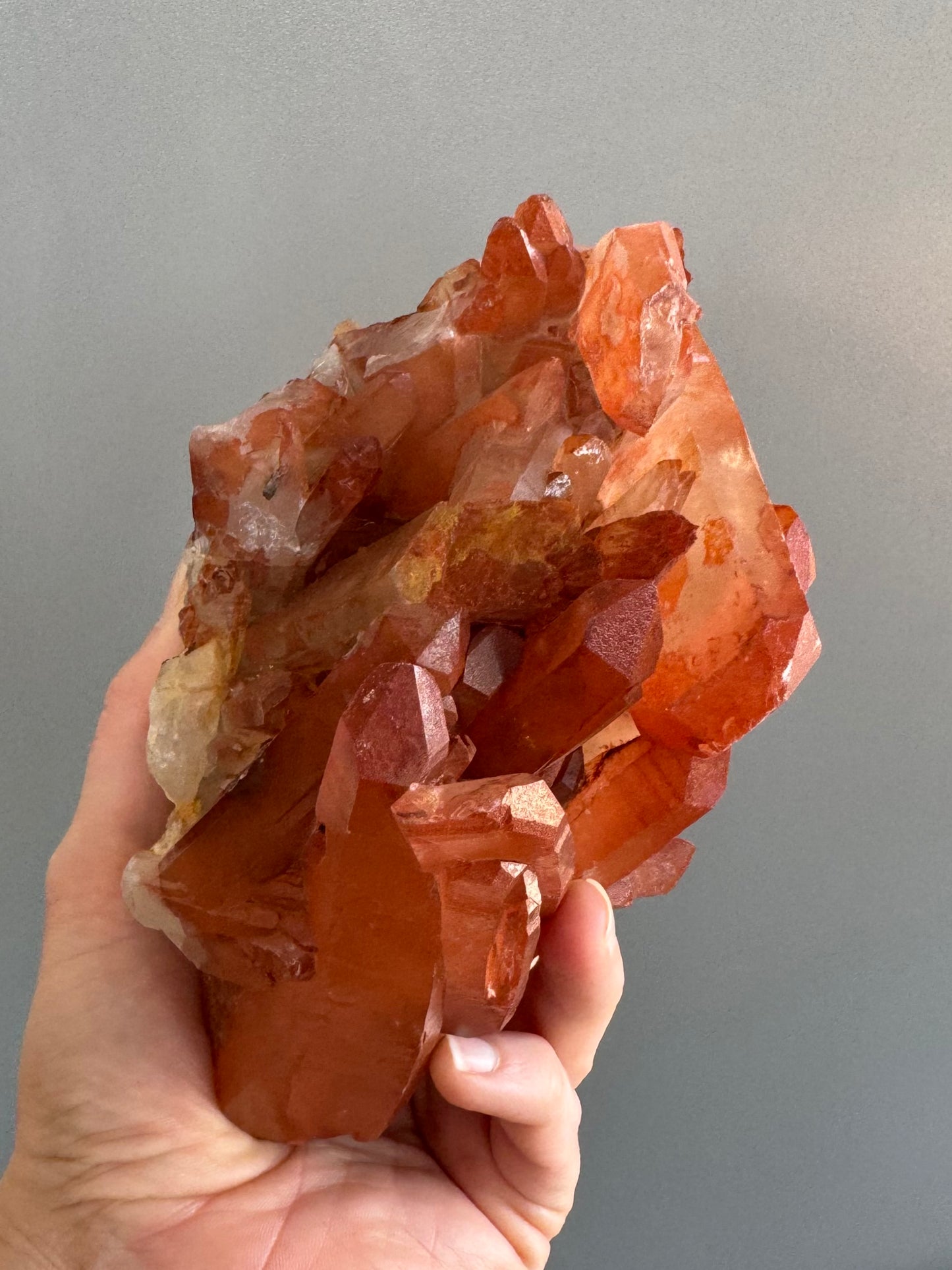 Looking down the top of the specimen, with saturated orange red color in indirect light. The sideways crystal is red at the end but colorless on the rest of the back.