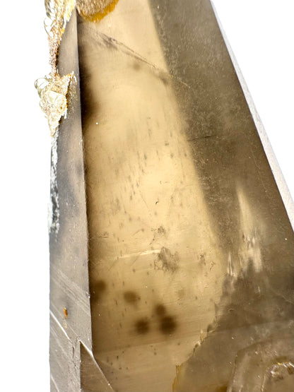 Detail of a face of the quartz, a matte surface. It has good clarity with small spot inclusions and a few larger spots of the black coloration