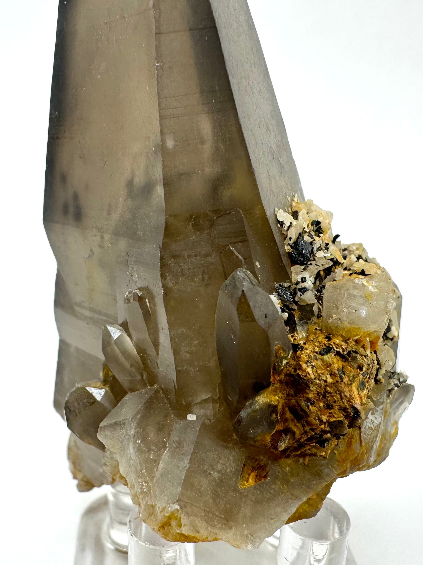 Detail of the cluster of smoky quartz at the base, a good spray of stubby crystals. There are black and white minerals on the right face, and some orange iron-staining.