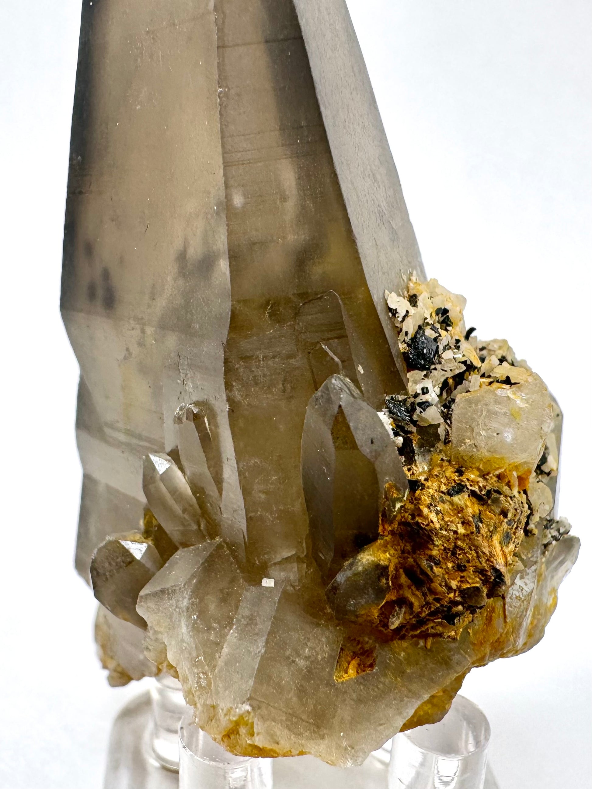 Detail of the cluster of smoky quartz at the base, a good spray of stubby crystals. There are black and white minerals on the right face, and some orange iron-staining.