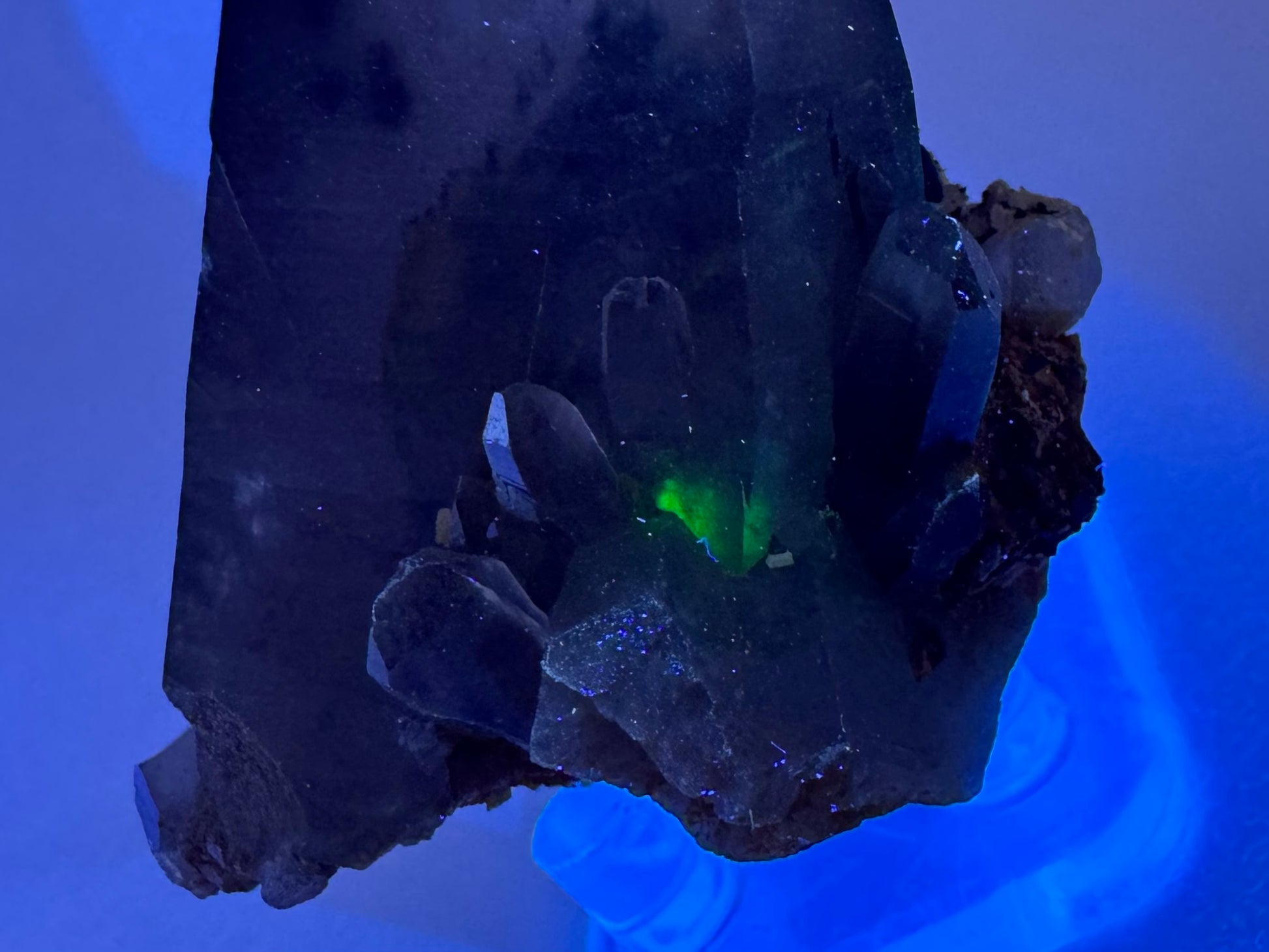 Detail of the base of the point in the dark under UV light, with a spot of green glow inside the quartz.