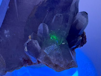 Detail of the base of the point in the dark under UV light, with a spot of green glow inside the quartz.